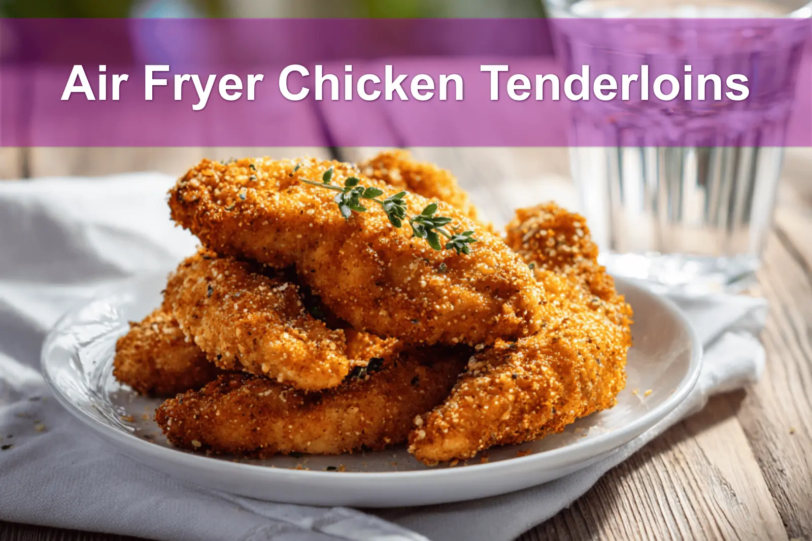 Air Fryer Chicken Tenderloins plated on white cloth napkin with clear glass of water and herbs