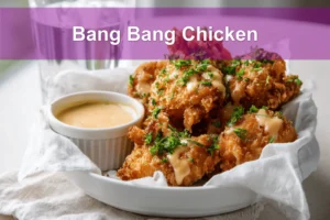Bang Bang Chicken golden crispy pieces drizzled with sauce and fresh herbs on white cloth