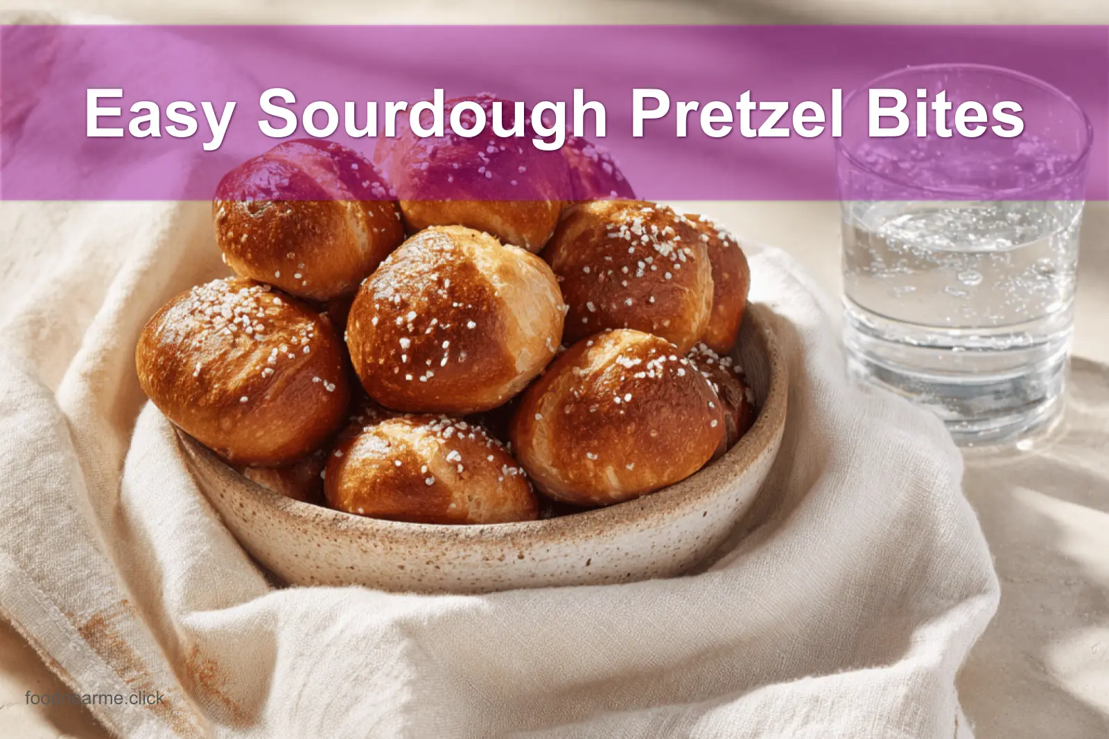 Golden-brown Easy Sourdough Pretzel Bites on white napkin with glass of water beside.