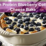 High Protein Blueberry Cottage Cheese Bake plated on white cloth with fresh blueberries and graham crumbs