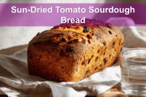 Sun-Dried Tomato Sourdough Bread on white napkin with water glass beside it.