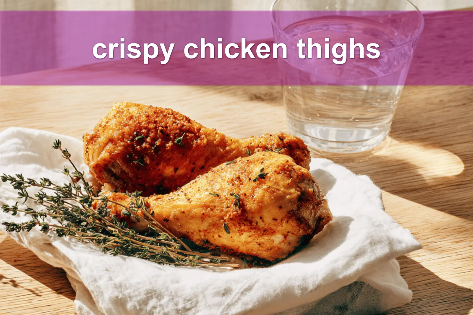 Crispy chicken thighs plated on white cloth with clear glass of water warm natural light