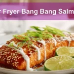 Air Fryer Bang Bang Salmon plated with sesame seeds lime wedges and green onions