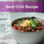 Beef Chili Recipe hearty bowl with shredded cheese fresh herbs jalapeños on white napkin
