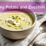 Creamy Potato and Zucchini Soup in white bowl on linen garnished with thyme and melted cheddar