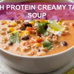HIGH PROTEIN CREAMY TACO SOUP in bowl with herbs lime wedges and melted cheese