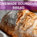 HOMEMADE SOURDOUGH BREAD golden crust loaf on white cloth with starter and glass of water