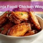 Ninja Foodi Chicken Wings on white napkin with clear glass of water and golden glaze