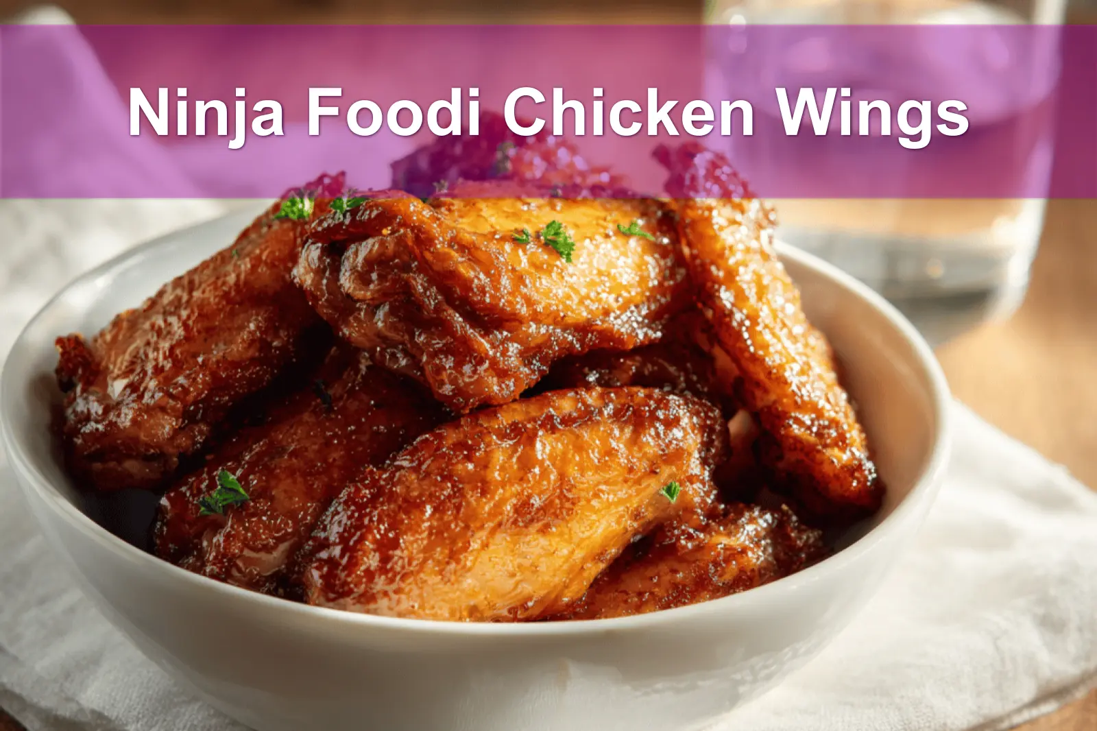Ninja Foodi Chicken Wings on white napkin with clear glass of water and golden glaze