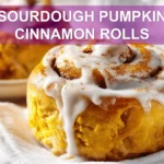 SOURDOUGH PUMPKIN CINNAMON ROLLS glazed rolls on white cloth with clear water glass