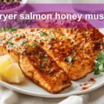 air fryer salmon honey mustard plated with lemon wedge and fresh herbs on white napkin