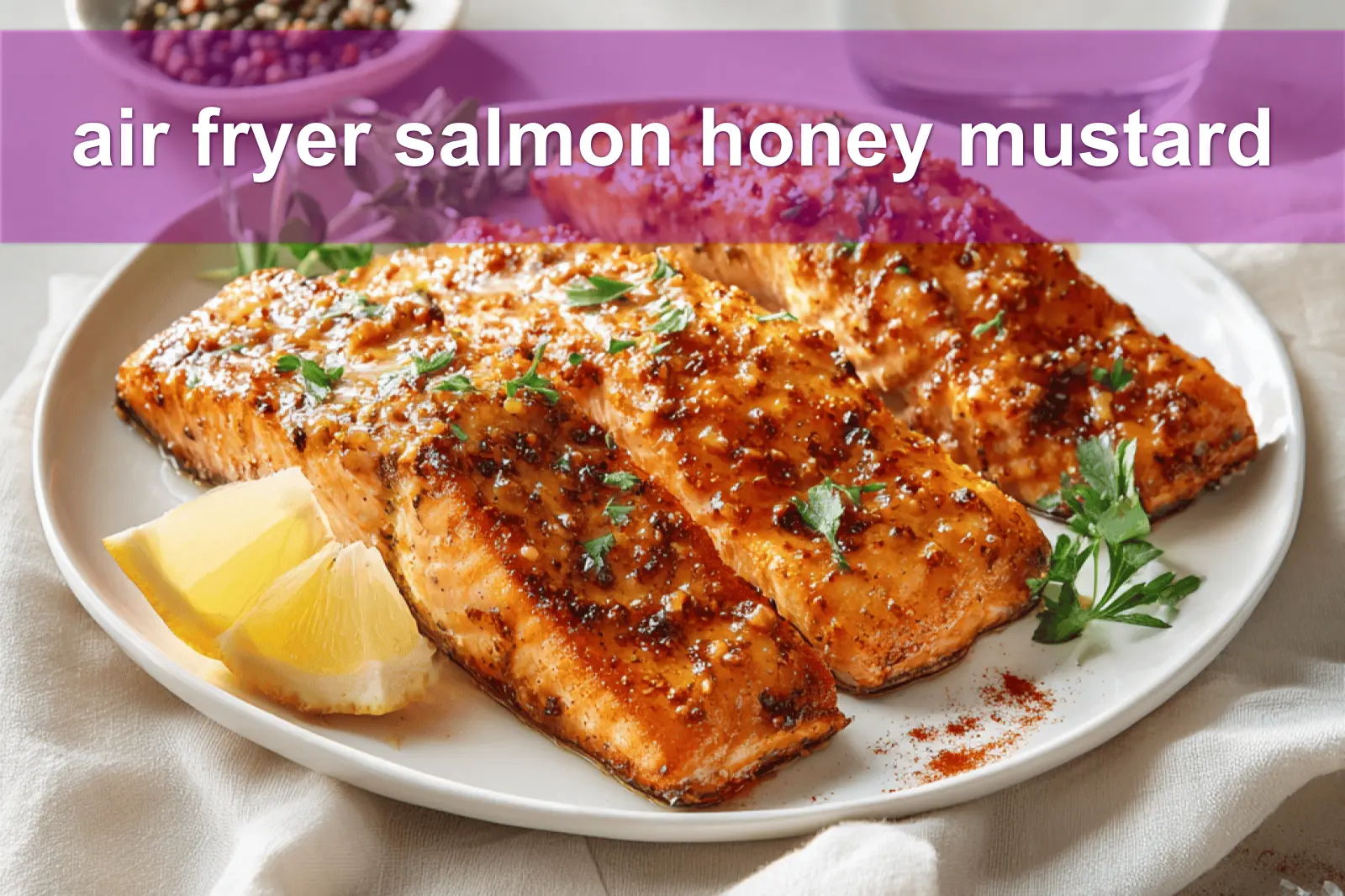 air fryer salmon honey mustard plated with lemon wedge and fresh herbs on white napkin