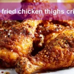 pan fried chicken thighs crispy golden skin on white cloth with simple glass of water