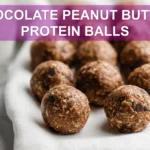 CHOCOLATE PEANUT BUTTER PROTEIN BALLS on white napkin with glass of water warm natural light
