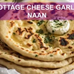 COTTAGE CHEESE GARLIC NAAN warm golden flatbreads on white napkin with a clear glass of water