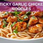 STICKY GARLIC CHICKEN NOODLES glazed chicken and noodles in warm bowl with green onions