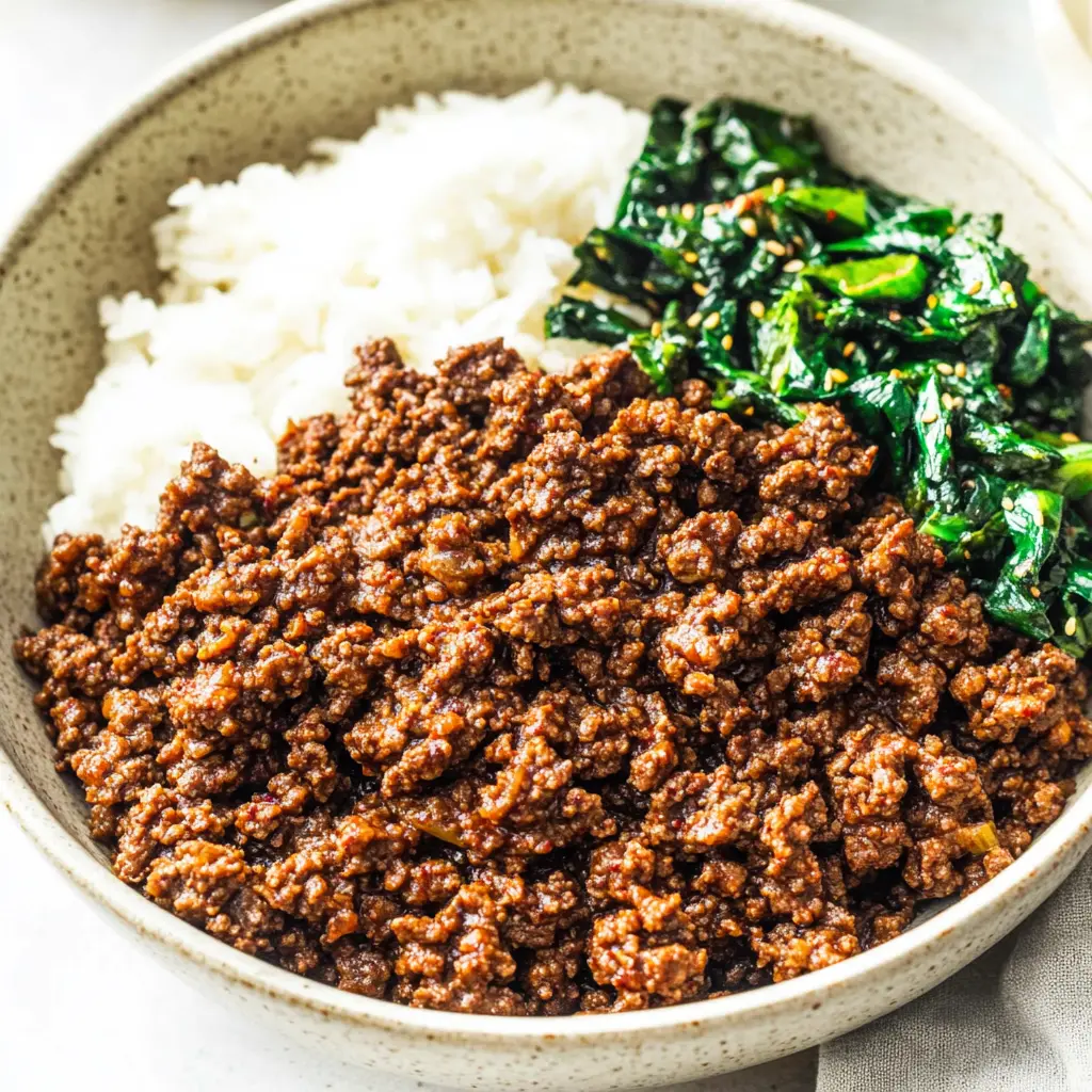 Korean ground beef bowl with cauliflower rice, cucumber, and sesame seeds in a white bowl